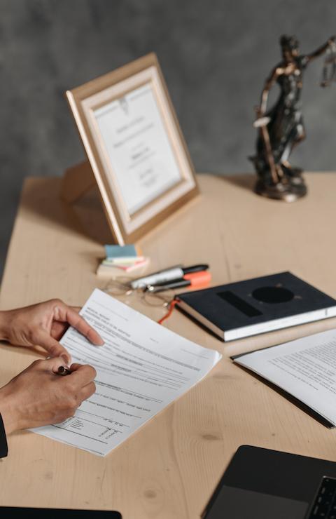 Un avocat en costume, assise à un bureau, discute avec une personne de l'autre côté de la table dans un environnement professionnel et formel.