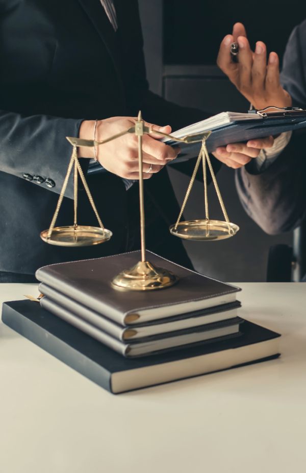Un avocat en costume sombre, assis à un bureau, examine des documents juridiques avec un marteau de justice posé à côté, symbolisant une scène de contentieux juridique.