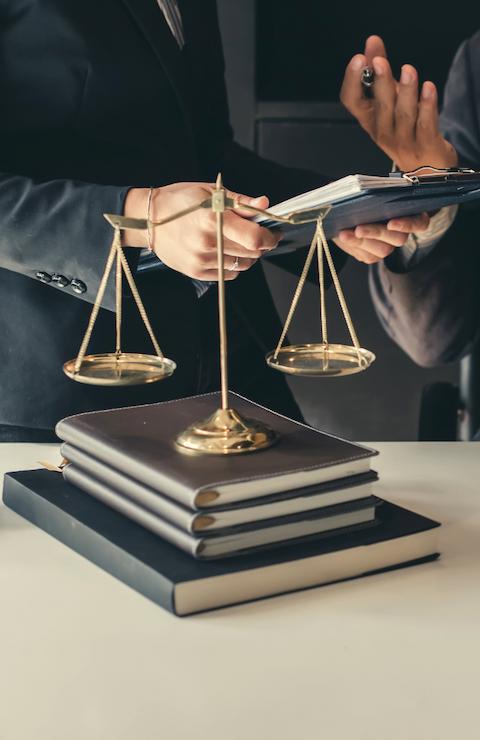 Un avocat en costume sombre, assis à un bureau, examine des documents juridiques avec un marteau de justice posé à côté, symbolisant une scène de contentieux juridique.